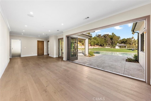 unfurnished living room with a healthy amount of sunlight, light wood-type flooring, and crown molding