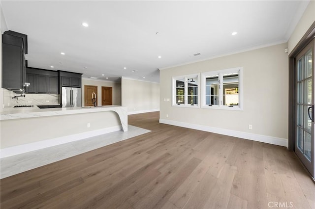 kitchen with stainless steel fridge, light hardwood / wood-style flooring, a wealth of natural light, and ornamental molding