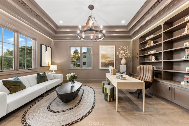 sitting room with a raised ceiling, light hardwood / wood-style flooring, a chandelier, and ornamental molding