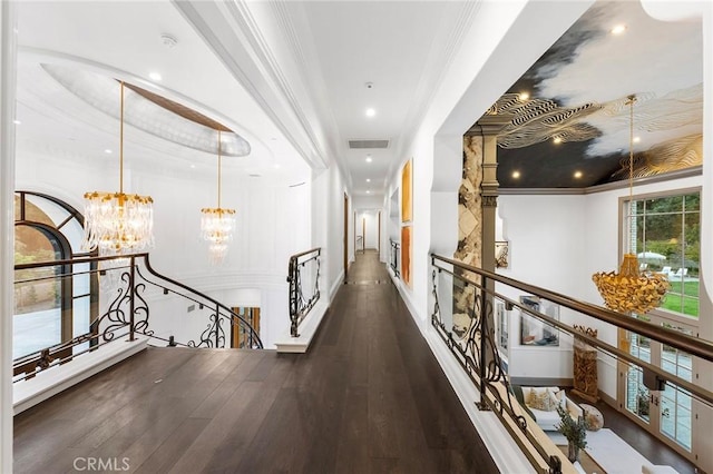 hallway with crown molding, dark wood-type flooring, and an inviting chandelier