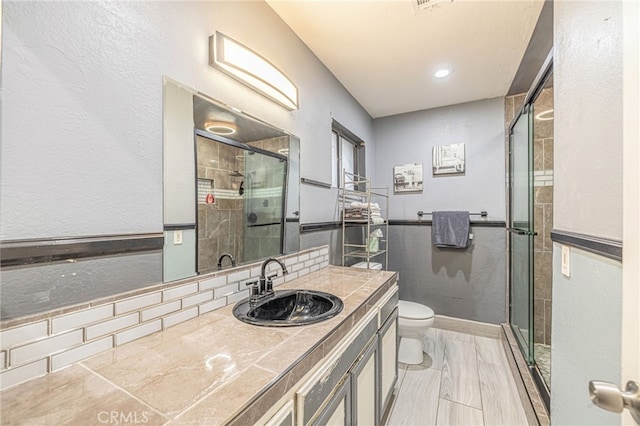 bathroom with vanity, a shower with shower door, and toilet