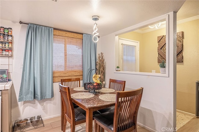 dining room with crown molding and light wood-type flooring