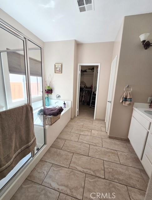 29822 Cool Meadow Dr, Menifee, CA 92584 - full bathroom with a bath, vanity, a walk in closet, and a shower stall