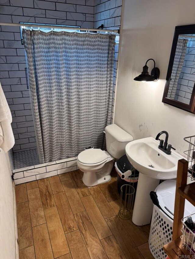 bathroom with a shower with curtain, toilet, and hardwood / wood-style flooring