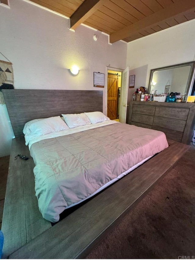 bedroom with beamed ceiling, carpet flooring, a barn door, and wooden ceiling