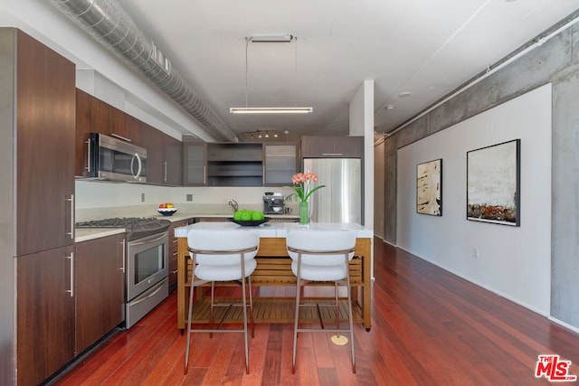 kitchen featuring a breakfast bar, dark wood-type flooring, and stainless steel appliances