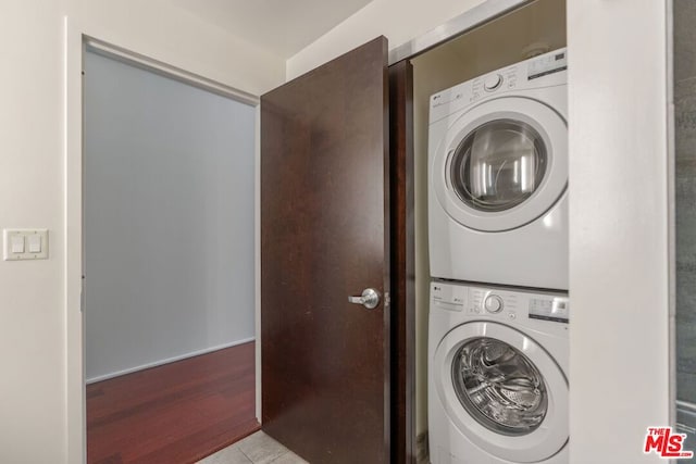 laundry room with light wood-type flooring and stacked washer and dryer