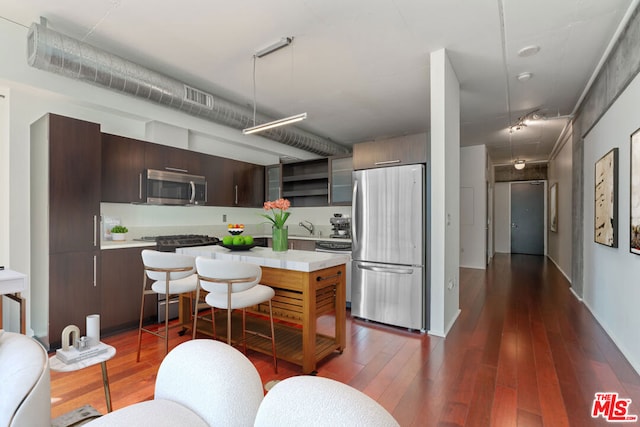 kitchen featuring appliances with stainless steel finishes, dark brown cabinetry, dark hardwood / wood-style floors, and sink