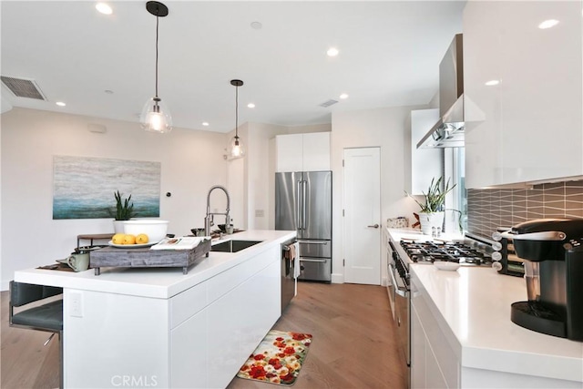 kitchen with white cabinetry, sink, a kitchen island with sink, and premium appliances