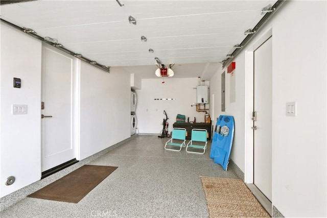 garage featuring water heater, a garage door opener, and stacked washer and clothes dryer