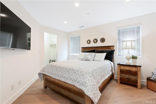 bedroom with a walk in closet and light hardwood / wood-style flooring