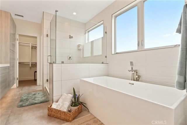 bathroom featuring shower with separate bathtub and tile walls