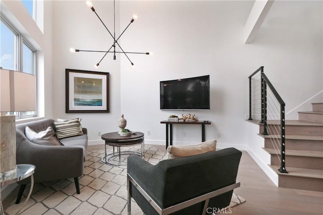 living room featuring a towering ceiling, a chandelier, and wood-type flooring