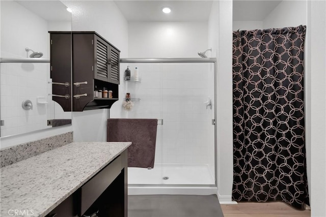 bathroom with a tile shower, vanity, and hardwood / wood-style flooring