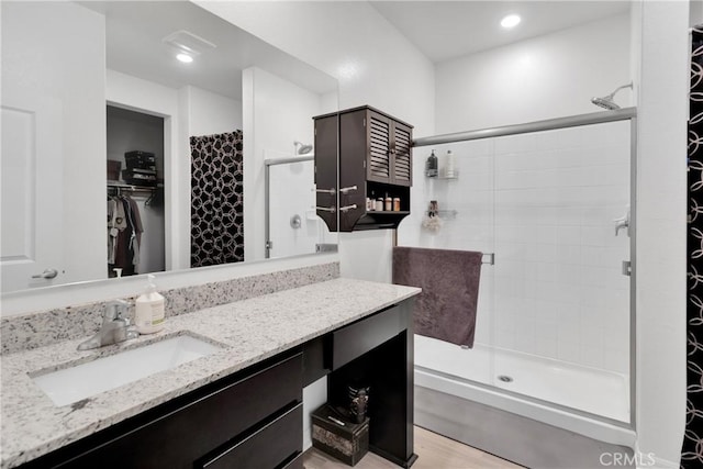 bathroom with a tile shower, vanity, and hardwood / wood-style flooring