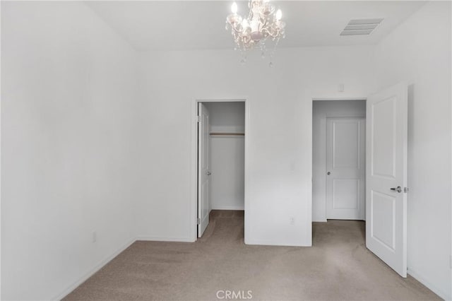 unfurnished bedroom with light carpet, a closet, and an inviting chandelier