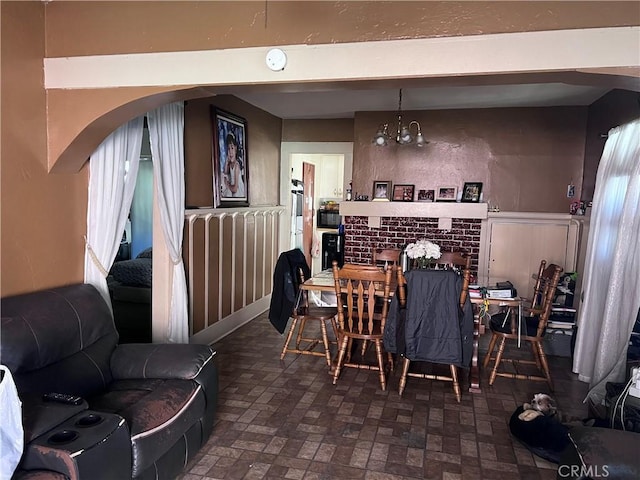 dining room with a brick fireplace and a chandelier