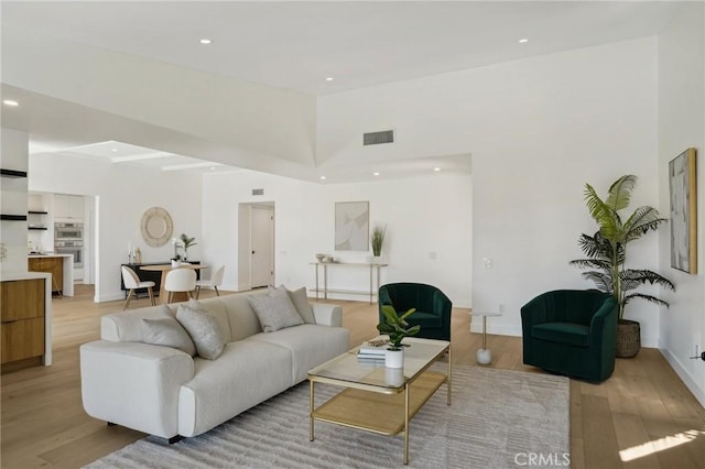 living room featuring a high ceiling and light hardwood / wood-style flooring