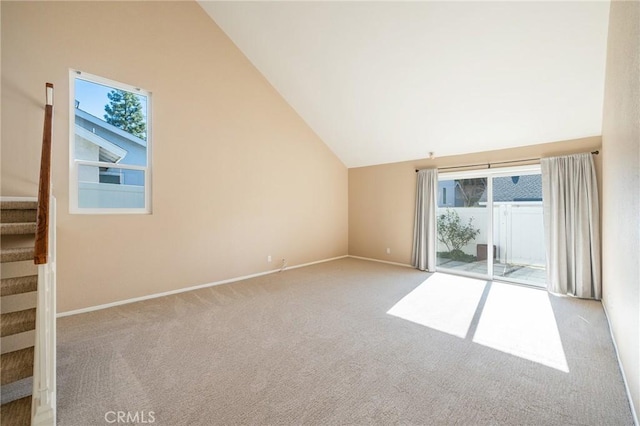 carpeted empty room with high vaulted ceiling