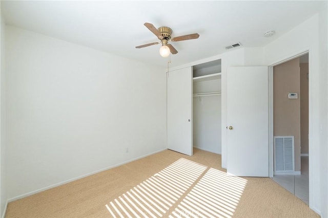 unfurnished bedroom featuring light carpet, a closet, and ceiling fan