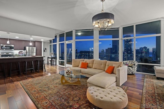 living room with a chandelier, dark hardwood / wood-style flooring, and a wall of windows