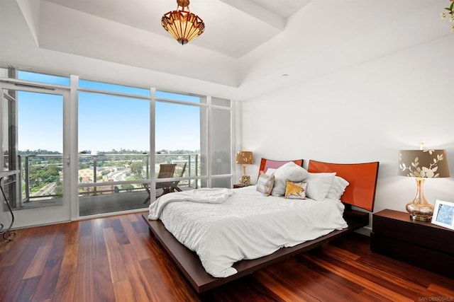 bedroom with access to exterior, a wall of windows, multiple windows, and dark wood-type flooring