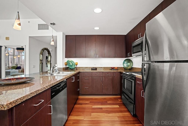 kitchen featuring sink, hanging light fixtures, light hardwood / wood-style floors, kitchen peninsula, and stainless steel appliances