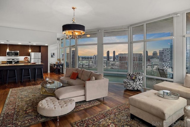 living room with dark hardwood / wood-style flooring, an inviting chandelier, and expansive windows