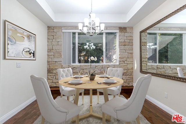 dining room featuring a tray ceiling, dark hardwood / wood-style flooring, and a chandelier