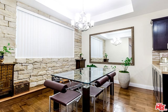 dining area featuring a notable chandelier, dark hardwood / wood-style floors, and a raised ceiling