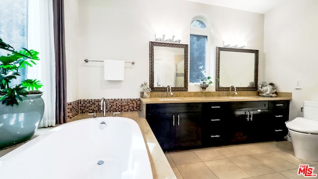 bathroom with vanity, toilet, tile patterned flooring, and tiled tub