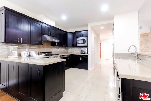 kitchen with stove, sink, stainless steel microwave, and backsplash