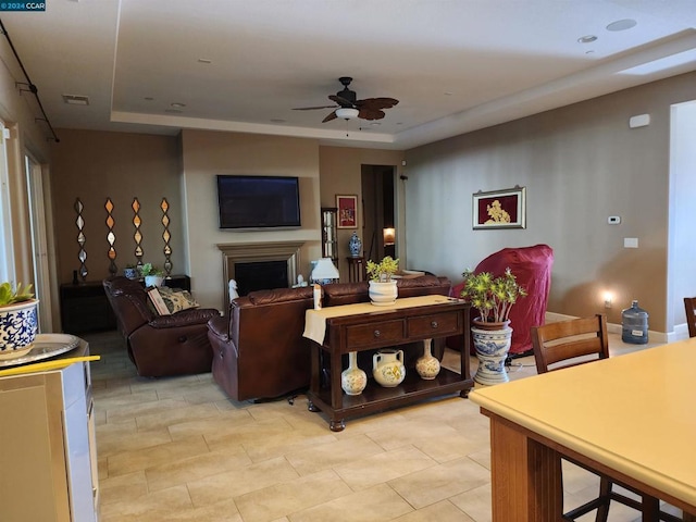 living room with a raised ceiling and ceiling fan