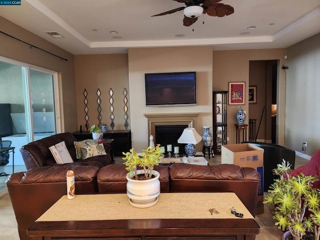 living room with ceiling fan and a raised ceiling