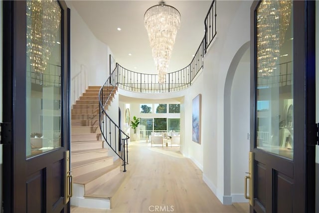1 Rue Du Parc, Newport Beach, CA 92660 - entrance foyer featuring a chandelier, stairway, light wood-style floors, arched walkways, and a high ceiling