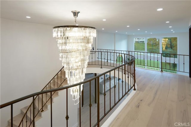 corridor with light hardwood / wood-style floors and an inviting chandelier