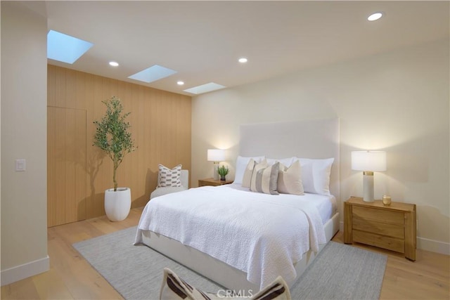 bedroom with a skylight and light hardwood / wood-style flooring