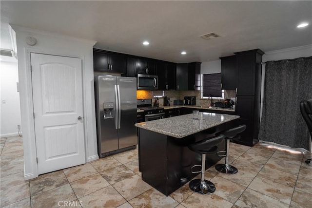 kitchen with a center island, light stone counters, crown molding, a breakfast bar area, and appliances with stainless steel finishes