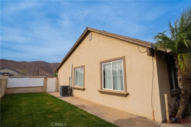 view of home's exterior with a lawn, a mountain view, and cooling unit