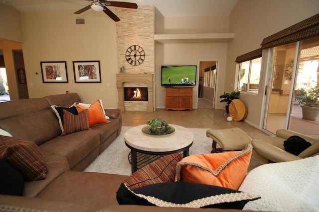 tiled living room with ceiling fan, a large fireplace, and lofted ceiling