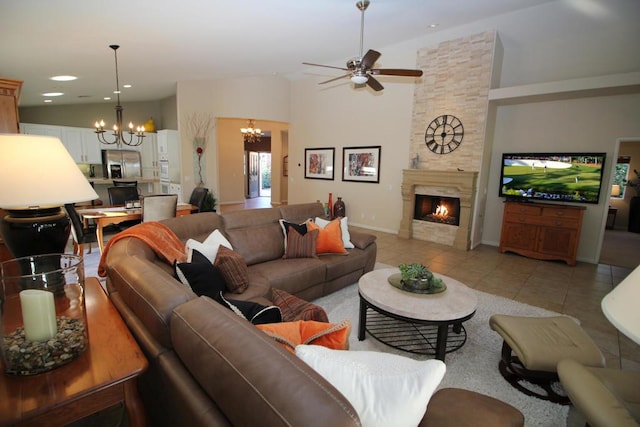 tiled living room with vaulted ceiling, ceiling fan with notable chandelier, and a stone fireplace