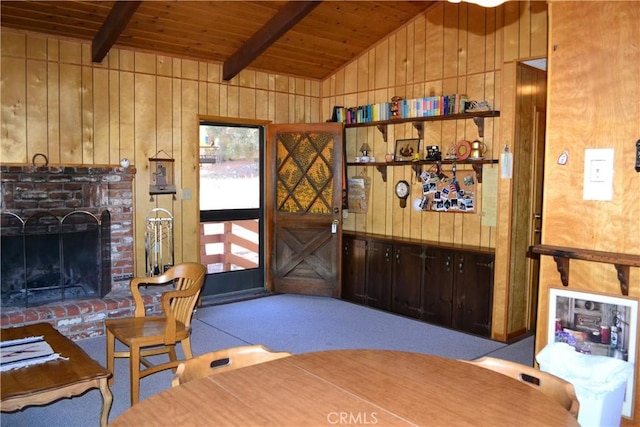 interior space with vaulted ceiling with beams, a brick fireplace, wooden walls, and wood ceiling