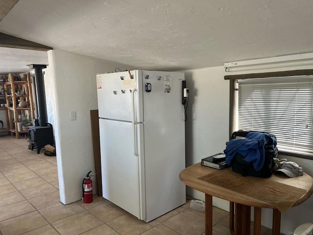 kitchen with white refrigerator, a wood stove, and light tile patterned floors