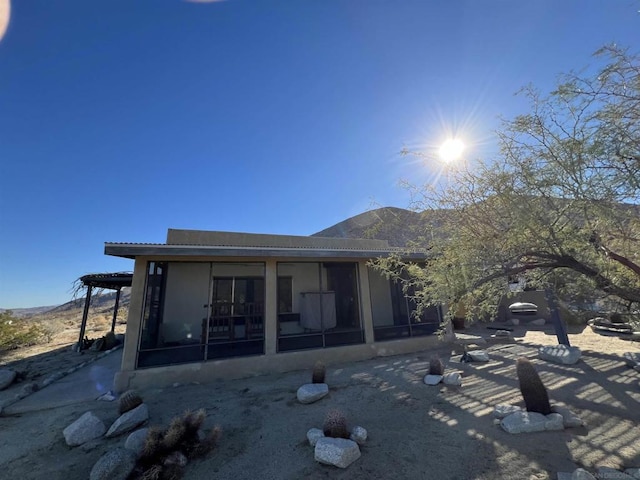 back of house featuring a sunroom, a mountain view, and a patio