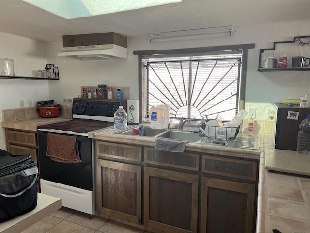 kitchen featuring ventilation hood, white electric range, sink, light tile patterned floors, and tile counters