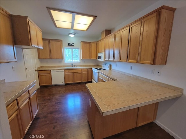 kitchen featuring tile counters, dark hardwood / wood-style flooring, white appliances, and kitchen peninsula