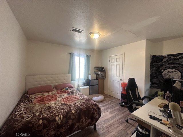 bedroom with a textured ceiling and hardwood / wood-style floors