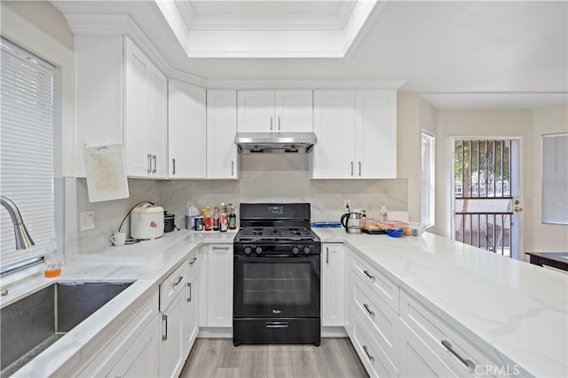 kitchen featuring light wood-type flooring, light stone counters, black range with gas stovetop, sink, and white cabinetry