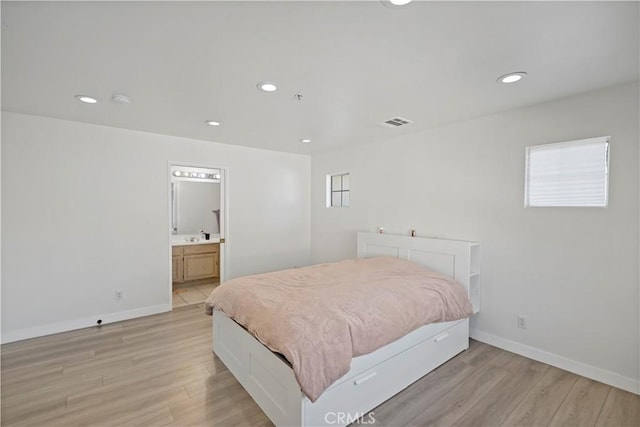 bedroom with ensuite bathroom and light hardwood / wood-style flooring