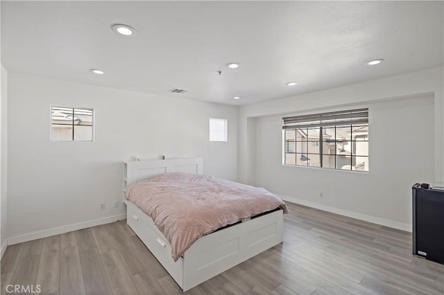 bedroom featuring multiple windows and light hardwood / wood-style flooring